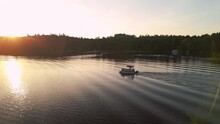 A pontoon motors out into a lake at sunset
