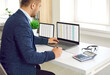 © Studio Romantic - Busy concentrated male financier working in office with Excel spreadsheets and calculator. Man sits in front of two laptops, fills out paper documents and enters data into electronic files.