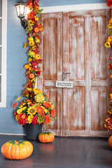 Wall Mural - Cozy wooden porch of house with pumpkin in fall. Halloween composition design home with yellow fall leaves and flowers. House entrance staircase decorated for autumn holidays, fall flowers and pumpkin