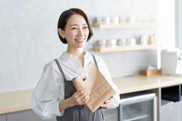 Wall Mural - カフェで紙袋を持つ女性店員　テイクアウト