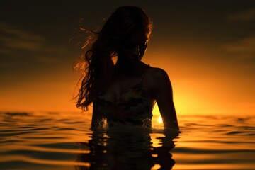 Wall Mural - woman standing in water at sunset