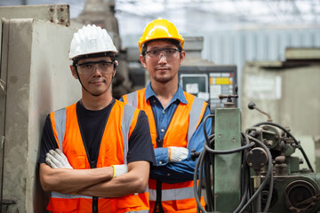 Wall Mural - Portrait of asian man engineer wear yellow helmet and uniform standing at industrial workshop. handsome workmen ​in factory. Copy space.