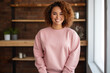 A happy plus size,  african woman, she is wearing a plain rose mockup unisex sweatshirt showcasing, brazilian woman at home.