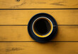 Black coffee cup and saucer on a yellow background. Minimalist concept. Viewed from above. AI generated