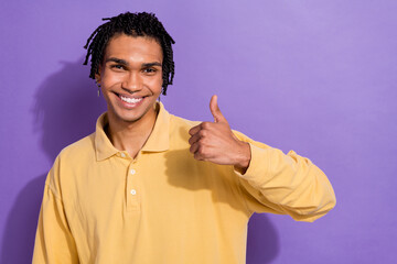 Wall Mural - Photo of satisfied cheerful man wear yellow stylish clothes arm thumb up nice feedback empty space isolated on purple color background