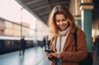 © Uzair - attractive woman traveler holding phone at railway or metro station