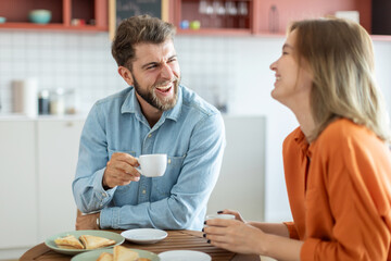 Happy european man and woman communication and laughing, sitting in cafe and drinking coffee, free space. First date concept