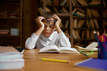 Little tired boy schoolchild falling asleep while doing homework