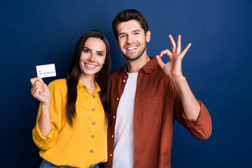 Wall Mural - Portrait of two cheerful nice people beaming smile hold debit card demonstrate okey symbol isolated on blue color background