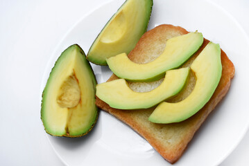 Wall Mural - Fried toast with slices of green avocado. A delicious lunch of bread and ripe avocado.