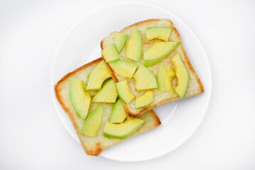 Wall Mural - Fried toast with slices of green avocado. A delicious lunch of bread and ripe avocado.