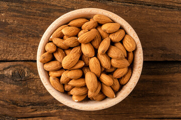 Wall Mural - Overhead shot of peeled almonds in bowl on wooden table. Healthy snacks