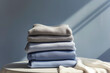 © ADDICTIVE STOCK - Generative AI illustration of stack of folded sweaters placed on table against wall in daylight