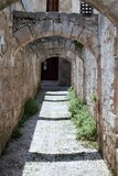 Fototapeta Na sufit - Cobblestone street of a medieval town with stone arches