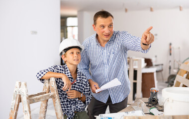 Wall Mural - Father and son talking about space planning in new apartment, pointing finger.