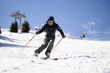 © Nikola Spasenoski - Professional skier skiing on slopes in a mountain winter resort. Sunny day with clear sky.