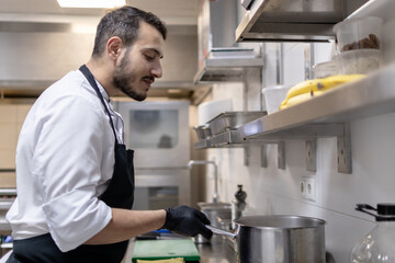 Wall Mural - Ethnic arab chef working in the restaurant kitchen with black gloves on his hands