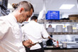 © Martin - Chef with a dread pigtail is looking at his mobile phone to look for a recipe
