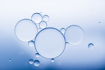 Oil and water bubbles created pattern and art image on soft blue background.