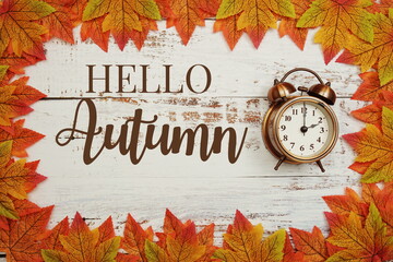 Canvas Print - Hello Autumn typography text with alarm clock and maple leaves on wooden background