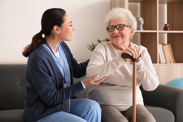 Wall Mural - Senior woman with stick and caregiver at home