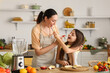 © Pixel-Shot - Little girl with her mother eating fruits while making smoothie in kitchen