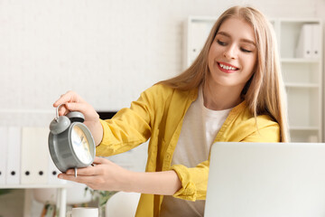 Wall Mural - Young businesswoman with alarm clock in office