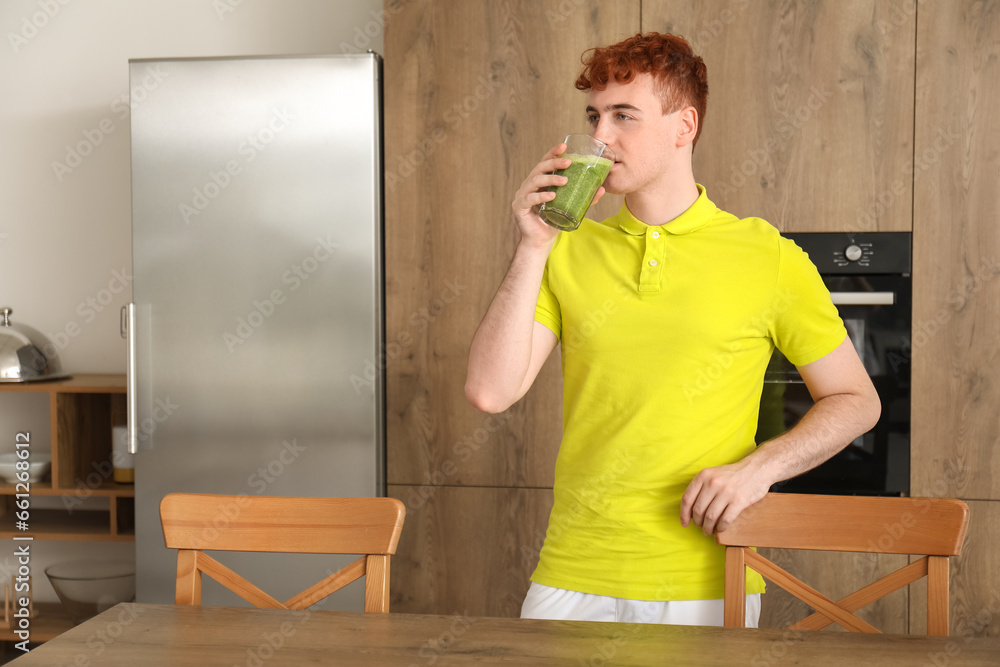 Young redhead man drinking juice in kitchen