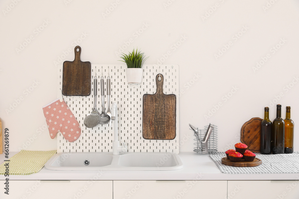 White kitchen counters with cutting boards, pegboard, sink and utensils