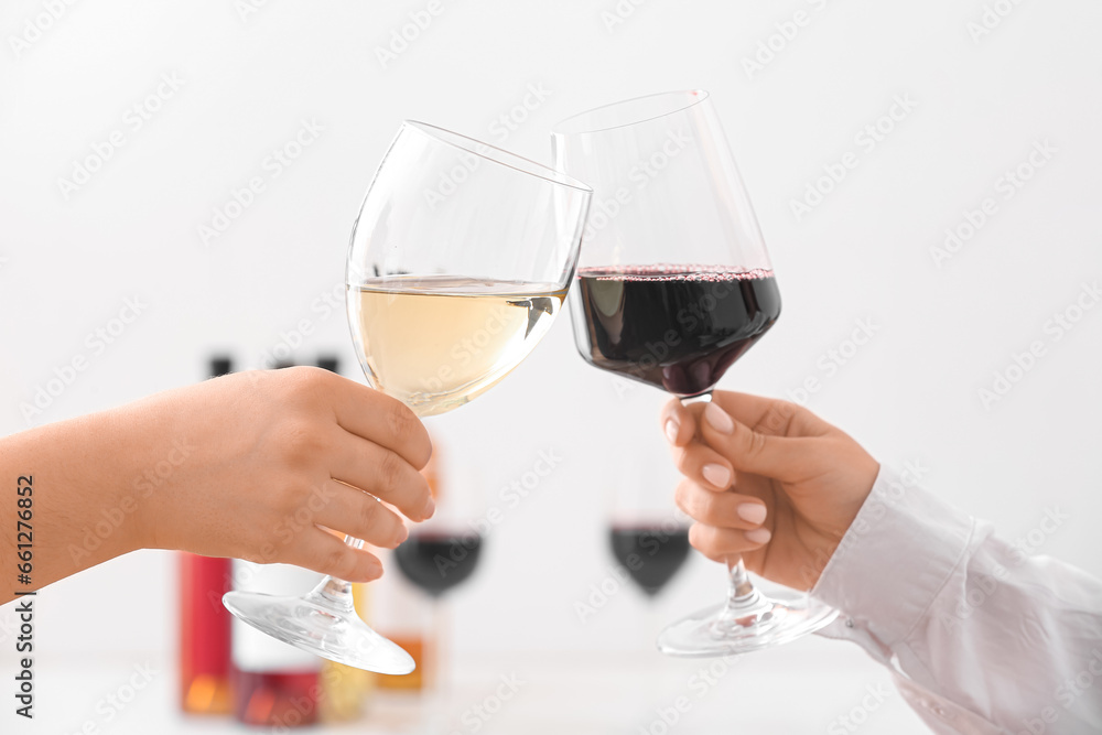 Female hands with glasses of different exquisite wine on light background