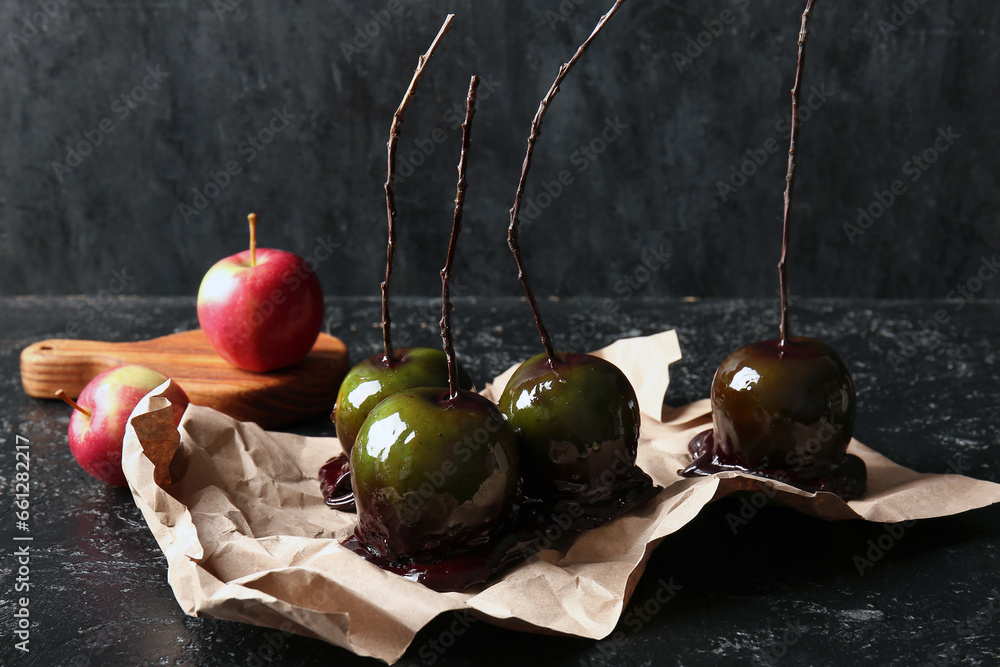 Tasty caramel apples for Halloween on black background