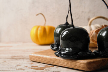 Wooden board of tasty caramel apples for Halloween on table