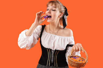 Poster - Young woman dressed for Halloween with candies on orange background