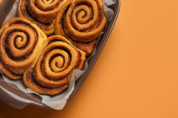 Wall Mural - Baking dish of tasty cinnamon rolls on brown background