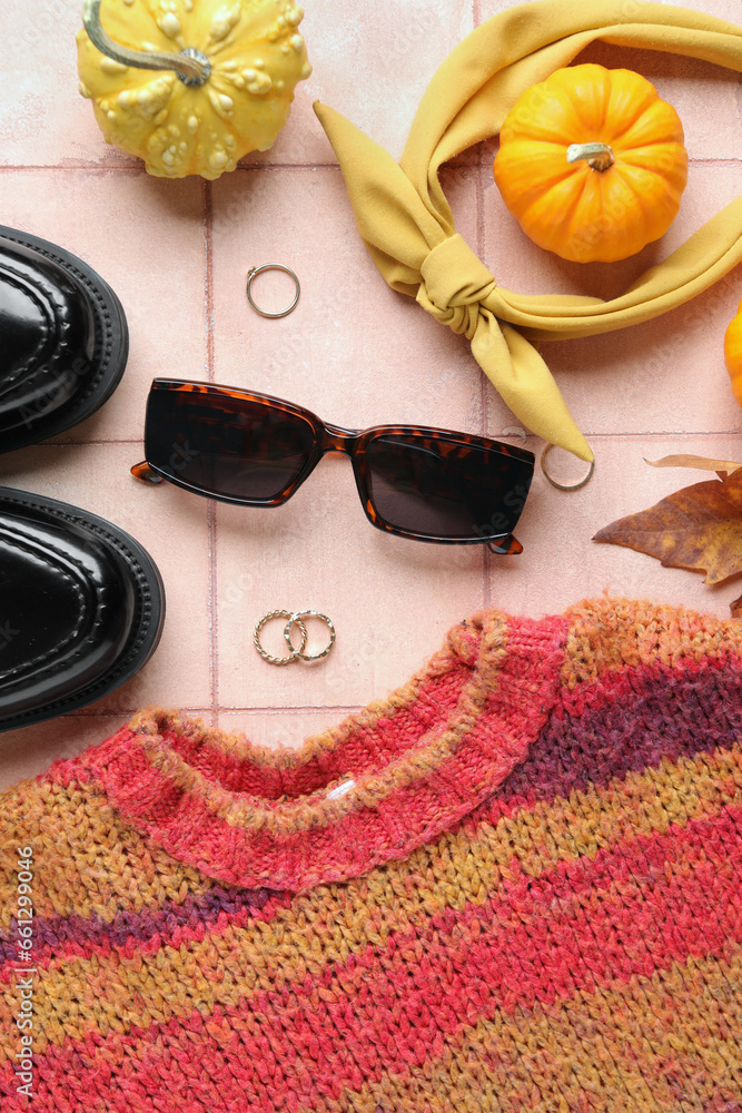 Composition with stylish female accessories, clothes and pumpkins on color tile background, closeup