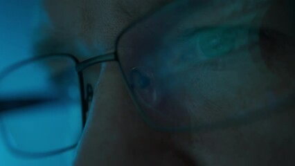 Close up portrait of software engineer working on computer. Line of hack code run in reflection on eyeglasses 