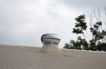Wall Mural - Close up of a roof top with a roof fan against a cloudy sky.