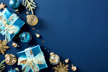 Stylish Christmas Card With Luxury Glistering Blue Paper Gift Boxes, Gold And Blue Xmas Balls Ornaments, Fir Branches, Confetti On Dark Blue Background. Flat Lay, Top View.