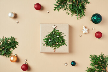 Wall Mural - Christmas gift box decorated fir branches and xmas balls ornaments on beige background. Flat lay, top view.