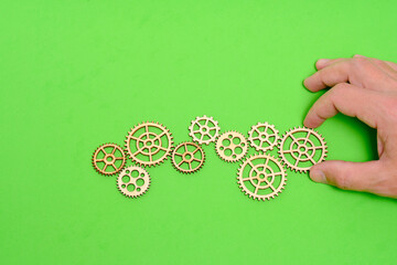 Hand on green background lays a gear. Concept industrial progress.