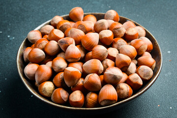 Wall Mural - Hazelnuts in a black stone bowl. Side view. Full frame of heap of hazelnuts. Close up.