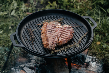 Wall Mural - grilling steaks on flaming grill, food on bonfire, cooking in the hike, outdoor activities