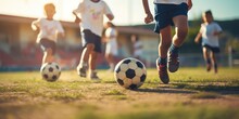 Close Up Of Kids Playing Football On Green Pitch. Kids Leg And Soccer Ball