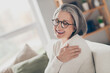 Photo of sweet adorable senior lady dressed white cardigan eyewear embracing herself closed eyes indoors house room