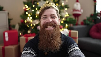 Poster - Young redhead man wearing king crown sitting by christmas tree at home