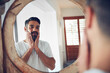 © Daniel L/peopleimages.com - Mature man, mirror and reflection in bathroom with thinking, wellness and beard for skincare, ideas and home. Person, morning and check face for beauty, health and facial hair with routine in house