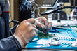 Cutting-edge electronics workshop scene showcases a skilled technician's hands meticulously soldering on a modern circuit board. Smoke rises tech-focused, emphasizing precision and high-tech expertise