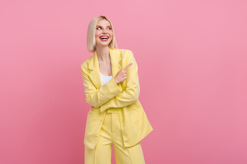 Photo of sweet excited woman dressed blazer suit looking pointing finger empty space isolated pink color background