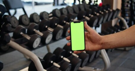 Male hand with smartphone in gym, fitness application results, green screen