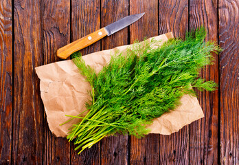 Wall Mural - Chopped fresh dill on a cutting Board and a bunch of dill preparation for freezing serving size organic healthy ething natural product portion on a wooden table. Top view,